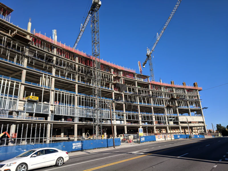 Edifício de múltiplos pavimentos em construção, com guindastes e estrutura de concreto